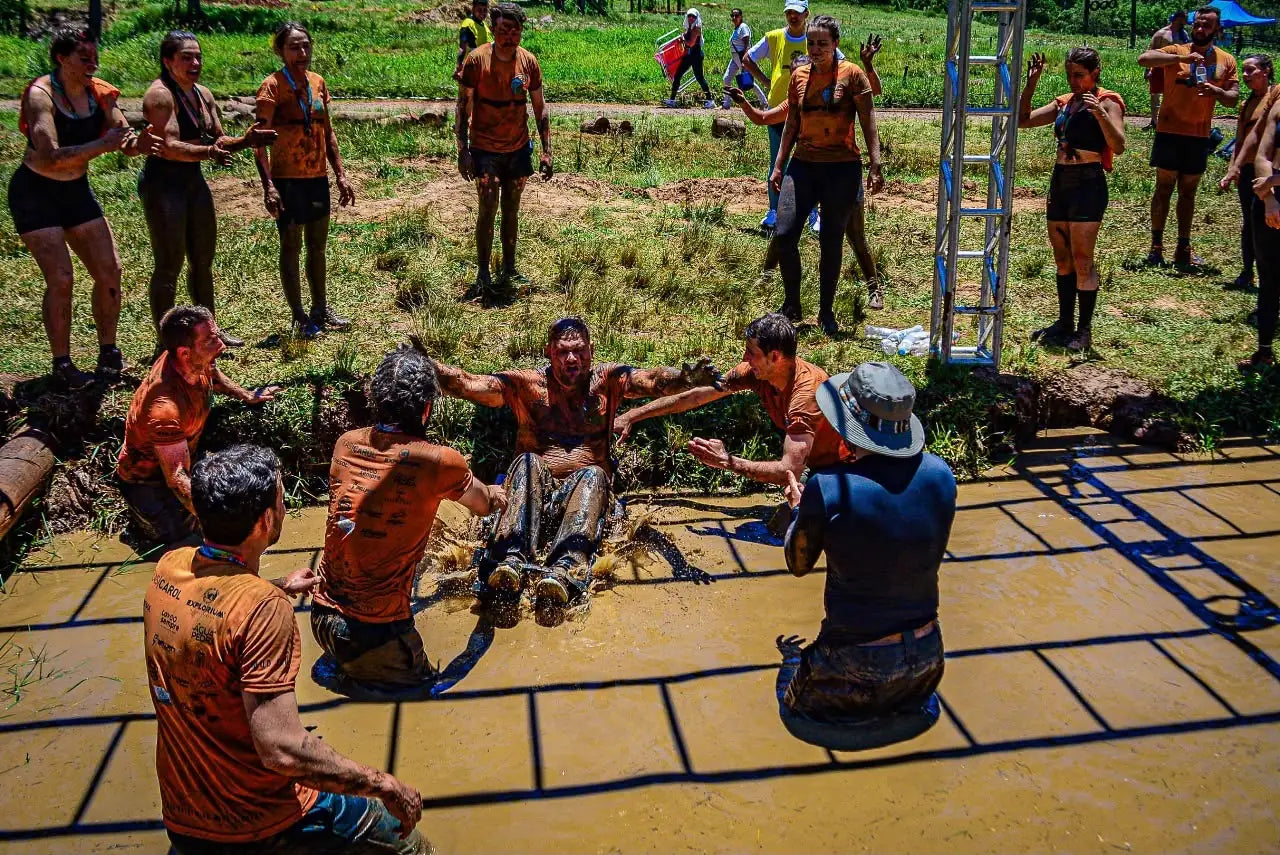 Grupo de atletas na lama celebrando durante a prova
